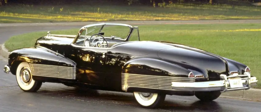 Black vintage Buick Y-Job concept car with streamlined design and white-wall tires on a test track