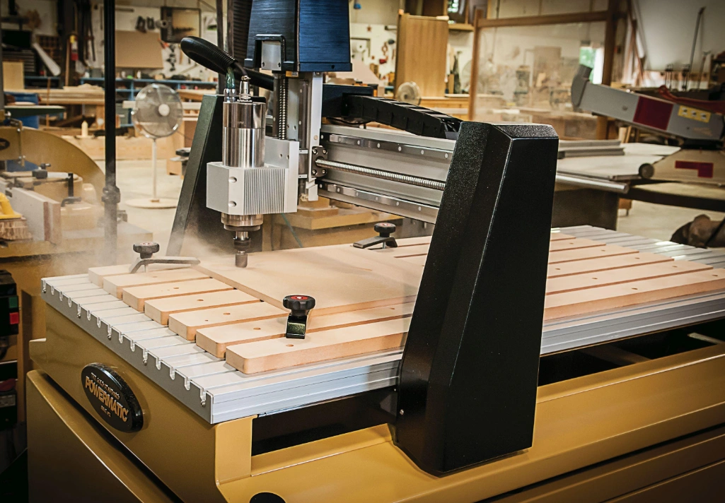 An image of a 3 axis CNC router machining a wooden block in a workshop environment