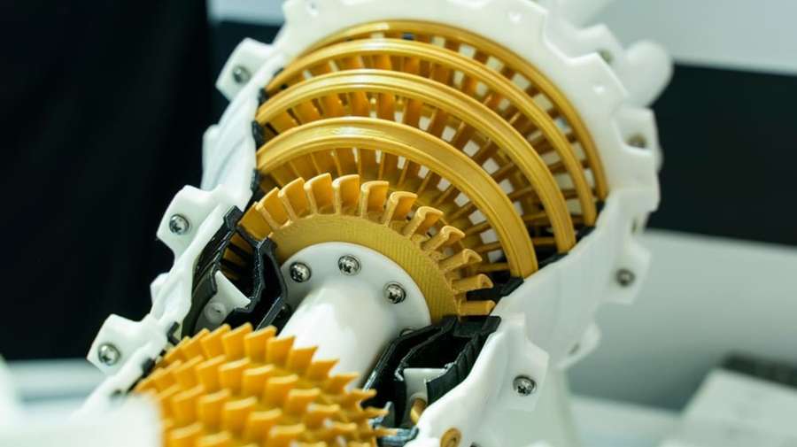 A close-up of 3D printed motorbike control unit component in yellow, showcasing its precise cuts