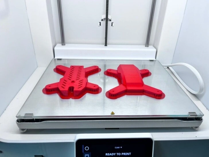 A close-up view of two drone enclosure sections lying on 3D printing bed