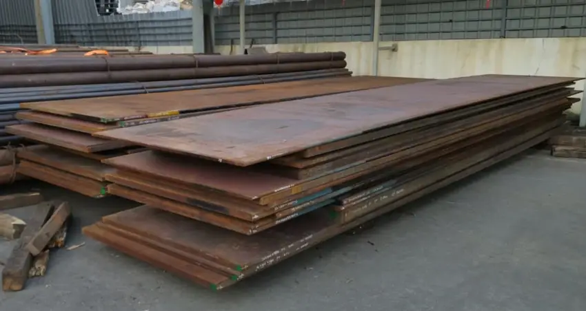 An image of two piles of thick corroded plates of 4140 steel on a floor