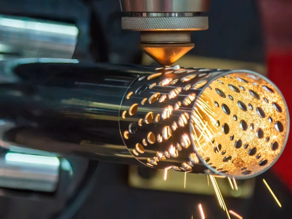 A closeup image of a CNC laser cutting process creating sharp round holes of different sizes in a metal tube