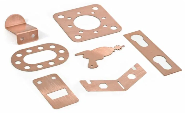 An image of copper parts of different shapes, sizes, and laser-cut holes