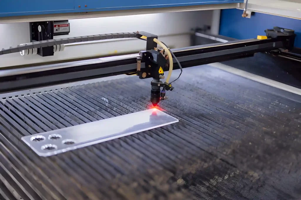 Closeup industrial CO2 laser cutting machine working with high powered red laser beam on acrylic.