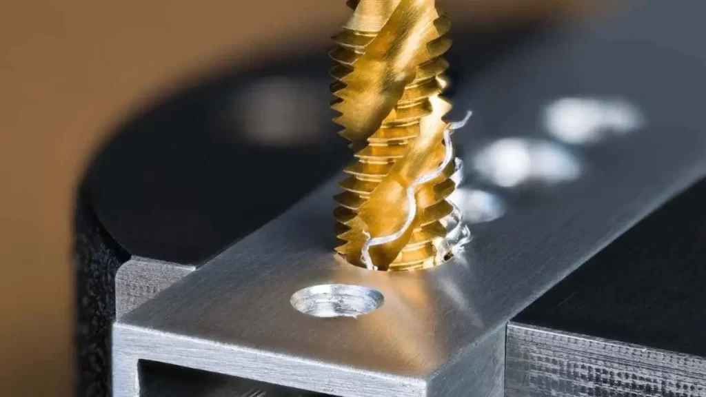 A close-up view of a broken tap inside a workpiece, showing signs of stress and damage.