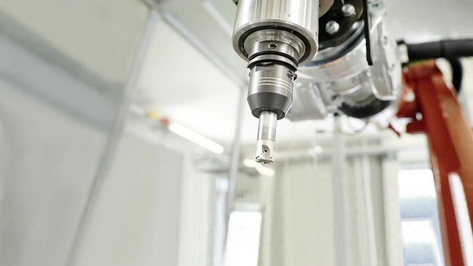 The image shows CNC machining in action with a robotic arm.