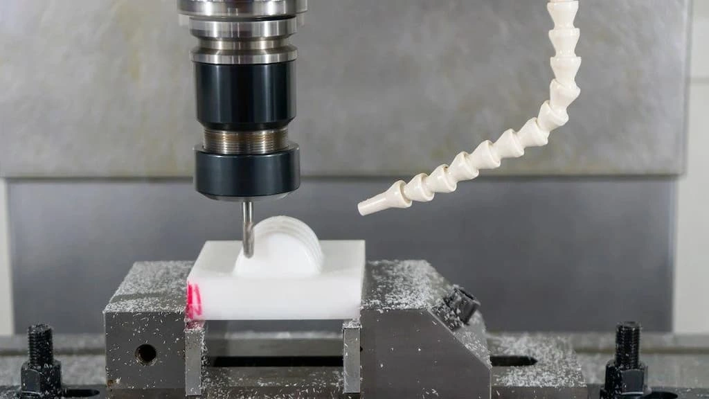 A close-up view of delrin machining on a milling machine; the end mill is shaping the workpiece