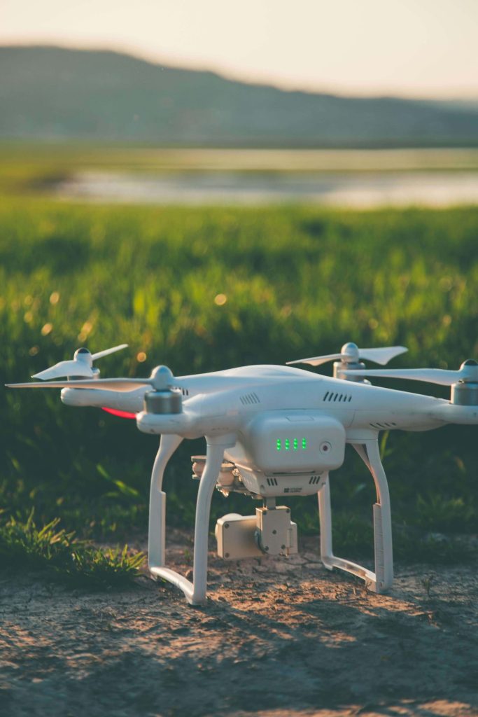 A white drone affixed with a camera resting on the ground