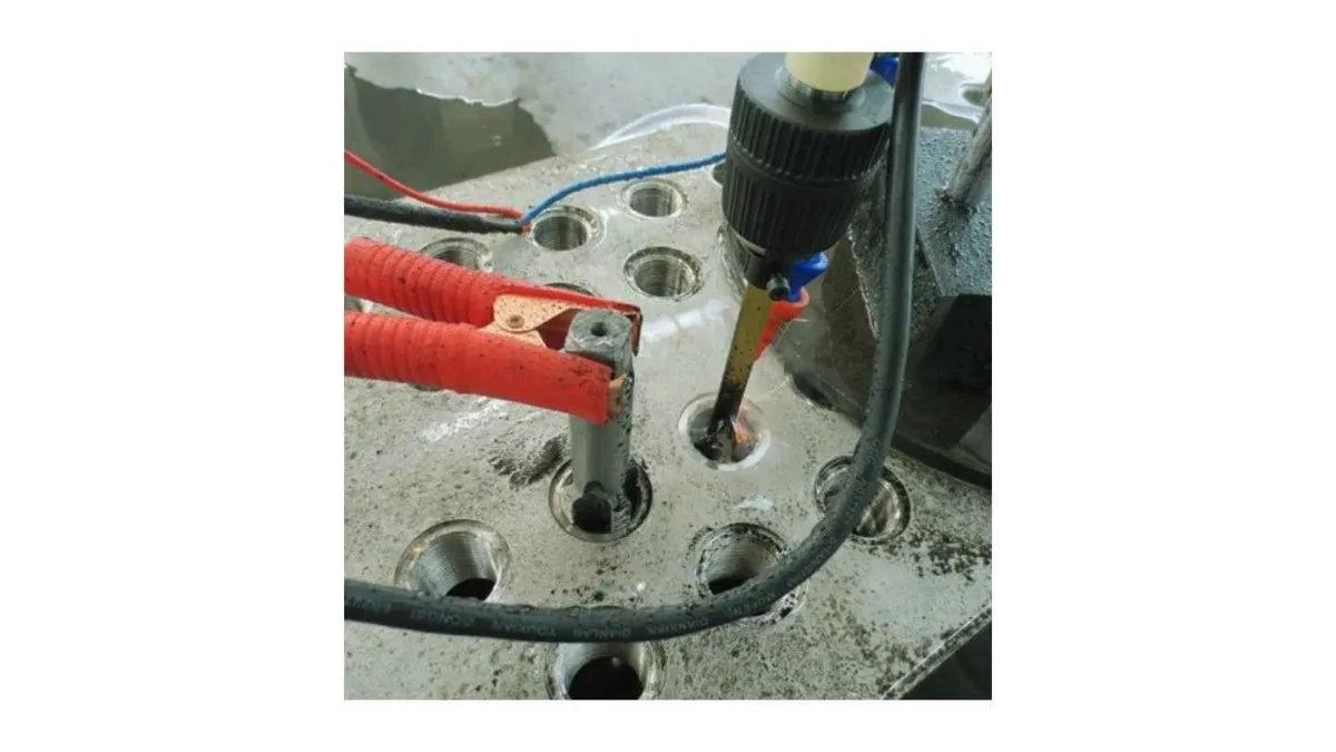 An image showing the EDM machine in operation to remove a broken tap from a workpiece.