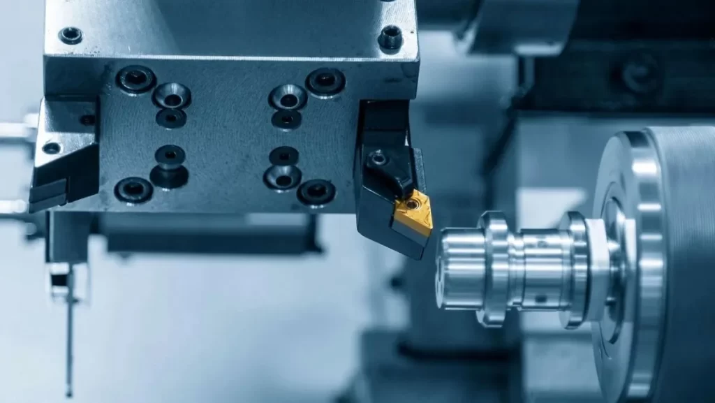 A close-up of a turning machine tool with a yellow insert, engaged with a metal part.