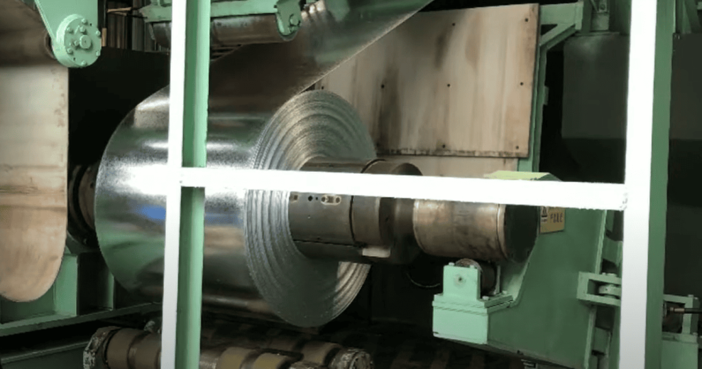 A close up view of galvanized metal sheet unrolling from coil
