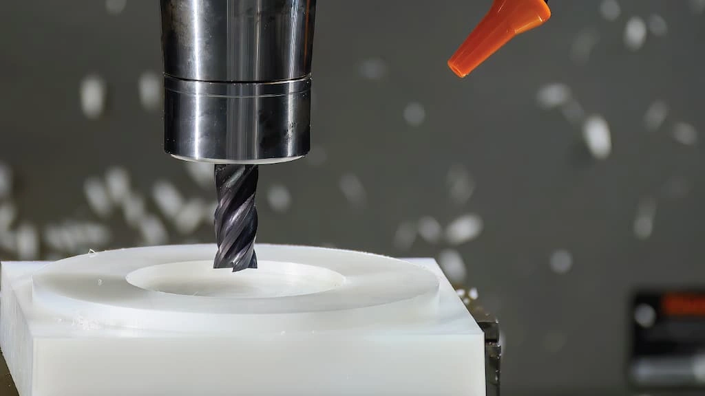 A close-up view of an end mill tool shaping the HDPE workpiece