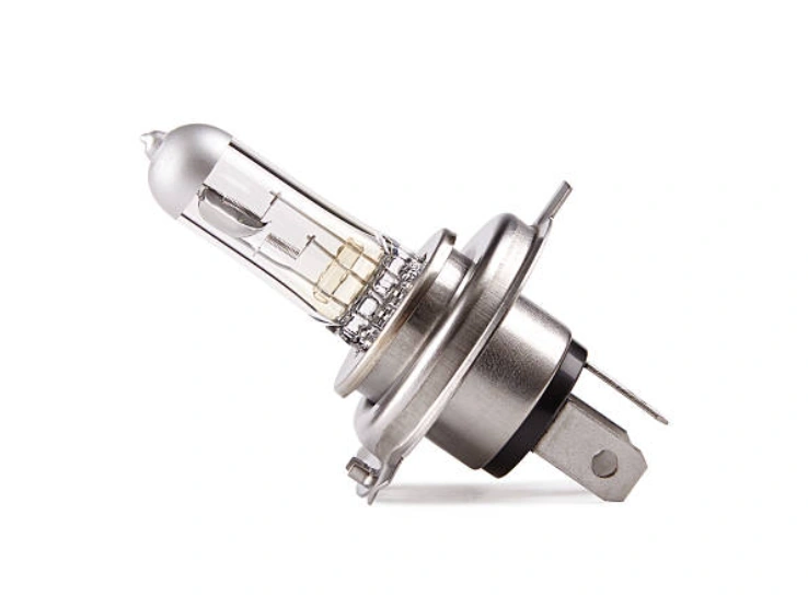 A closeup image of a halogen car headlight bulb on a white background