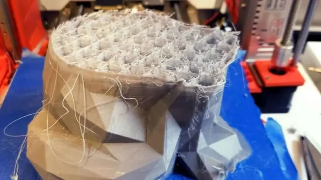 Close-up view showing heat creep in 3D printing, with layers of the printed part distorting due to excessive heat exposure.