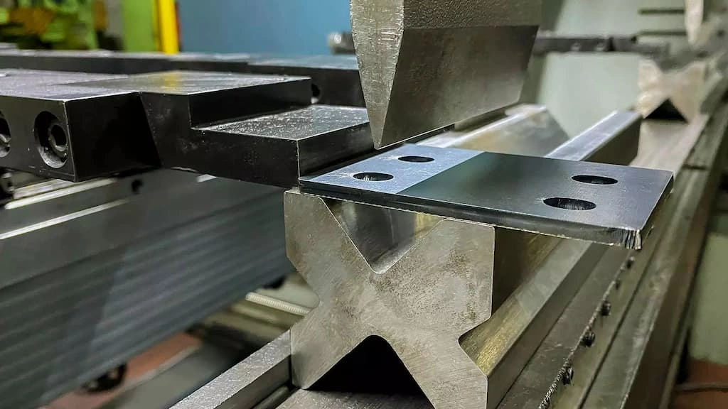 A close-up view of bending a thick steel sheet in a V-die