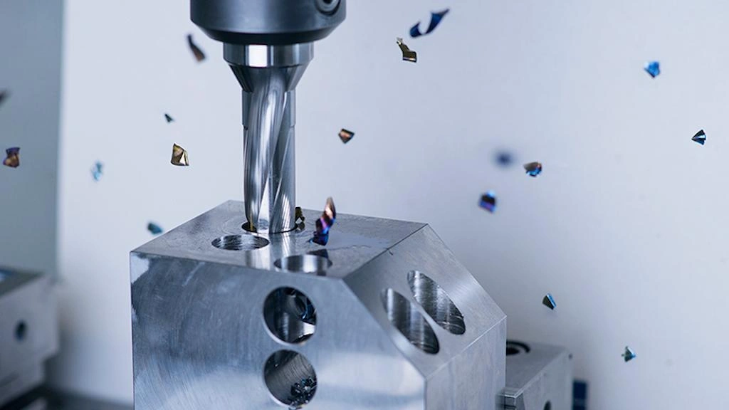 A close up view of drill bit making holes on steel wok with a long helical chip.