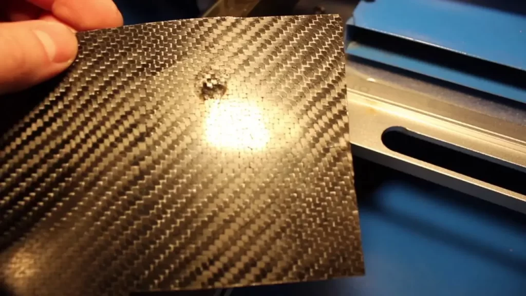 Burn mark on carbon fiber sheet from laser cutting.