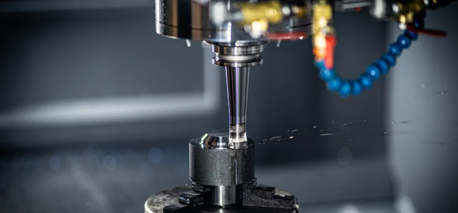 Close-up of milling machine cutter on a part with metal chips and coolant pipe