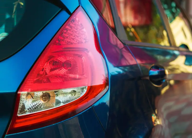 Red and clear PMMA tail light lens assembly on a blue car