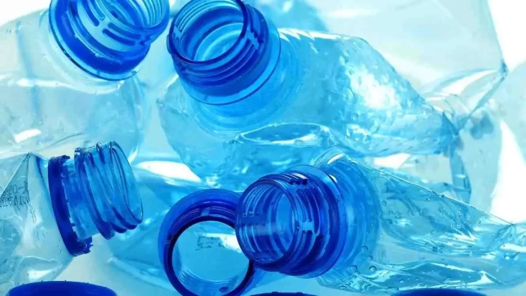 A pile of crumpled, transparent blue plastic bottles