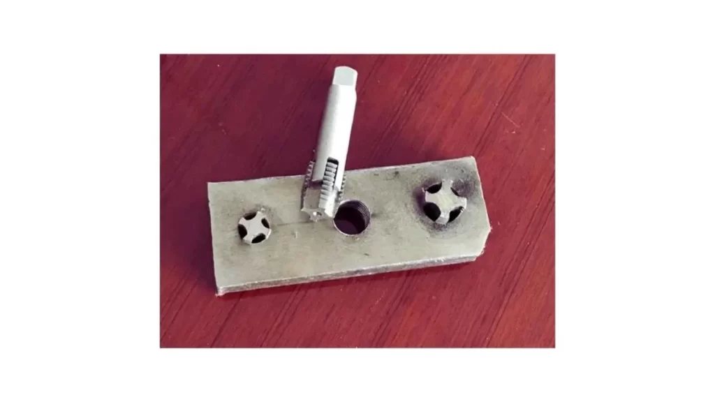 An image showing a punch being used to remove a broken tap from a workpiece.