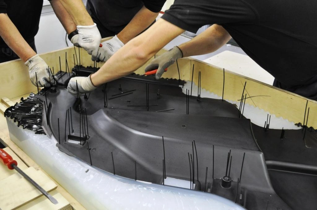 An image of operators ejecting a large-sized part from reaction mold.