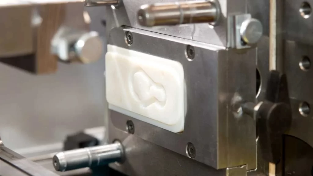 The image shows a soft tooling mold being set up for part production, with a molded part visible inside.