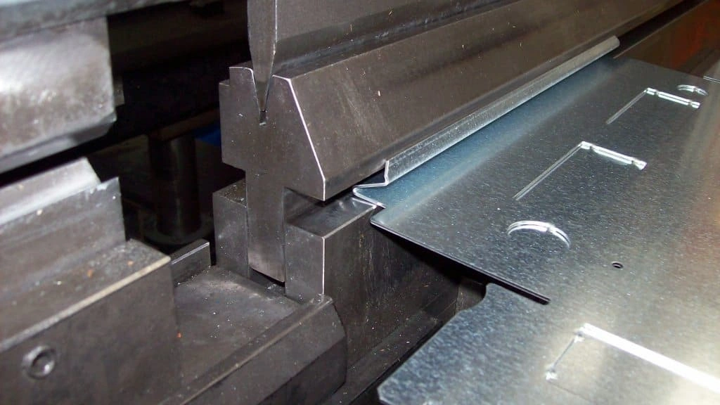 A closeup view of bending stainless sheet in a die and punch setup