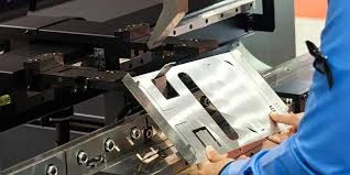 A close up view of an operator hand holding sheet metal part on die and punch for forming