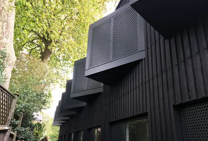 Black corrugated sheet metal facade with perforated architectural steel fabricated balcony enclosures