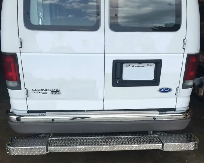 An image of the rear of a white van showing a metallic bumper with anti-slip patterns