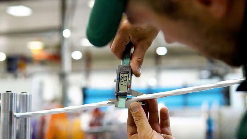 Person using caliper to measure thin white material.