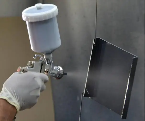 A close up view of an operator hand spraying teflon coat on metal surface