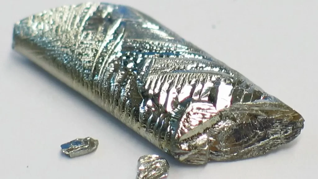 A close-up of a long, metallic, crystalline piece of the element tellurium.
