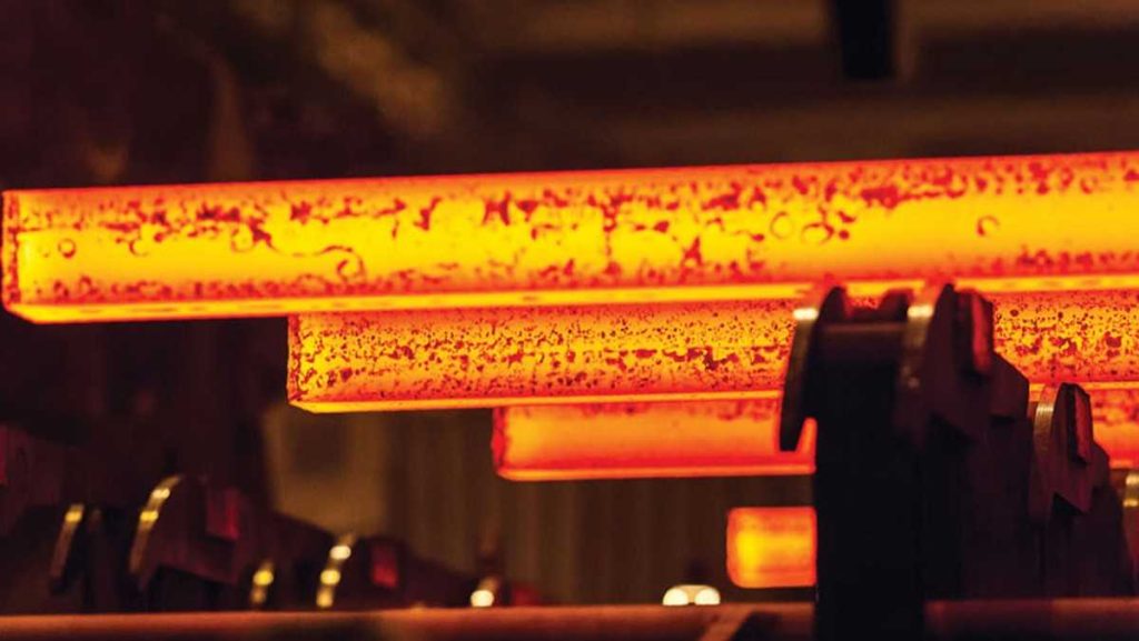 Close-up of glowing hot metal billets on a conveyor in a steel mill.