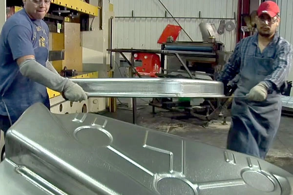 Two operators ejecting thick metal stamped parts from die setup