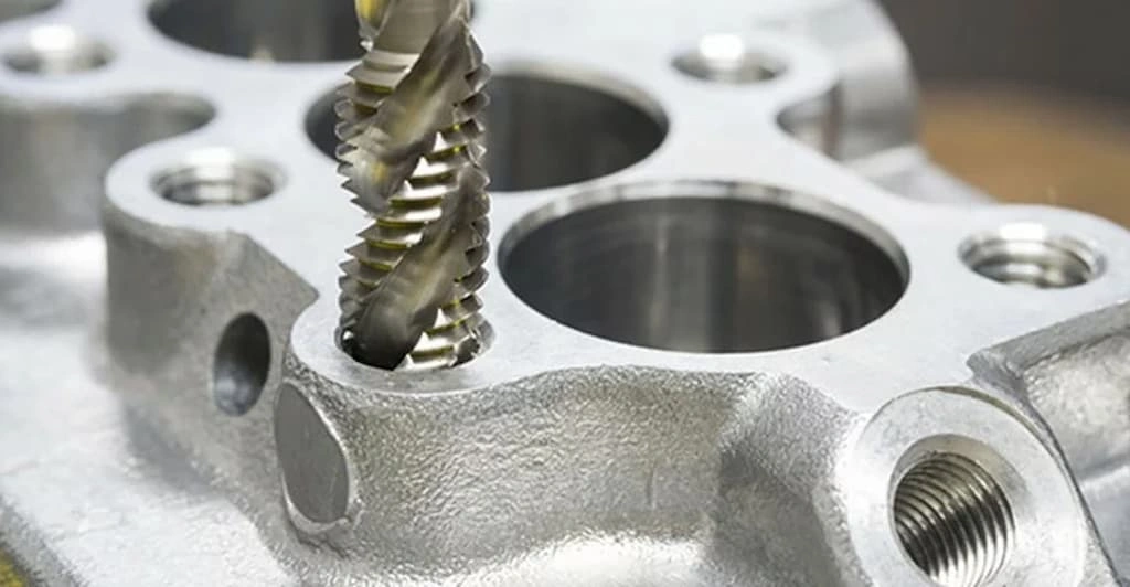 A close view of the CNC drill bit creating a hole on the zinc workpiece