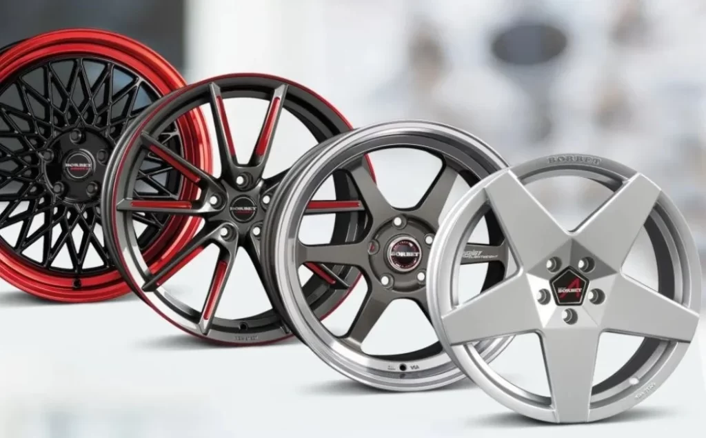 Four aluminum car wheels, two red and two silver, arranged in a line