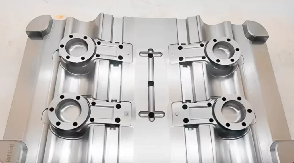 Top-down view of a precision-machined aluminum injection mold with four cavities and a central runner system.