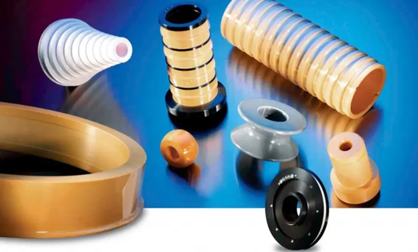 Assortment of CNC-machined ceramic parts, including ribbed tubes, stacked insulators, rings, and threaded components in various colors