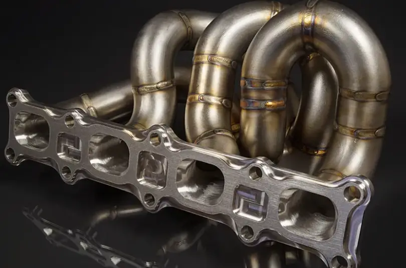 An image showing precision CNC-machined flanges on a metallic exhaust manifold