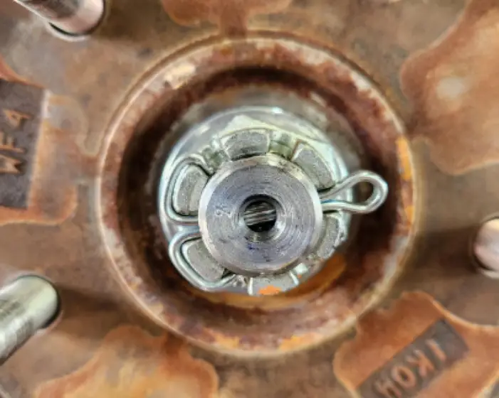 A metallic split pin visibly securing a wheel nut or axle component within a car wheel assembly