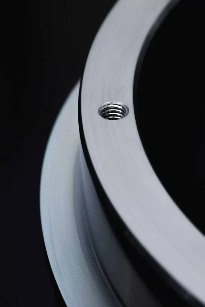 a section of a circular metallic part showing one threaded hole on the face