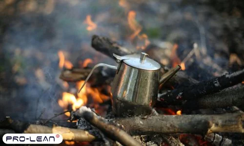 Stainless steel teapot on burning woods