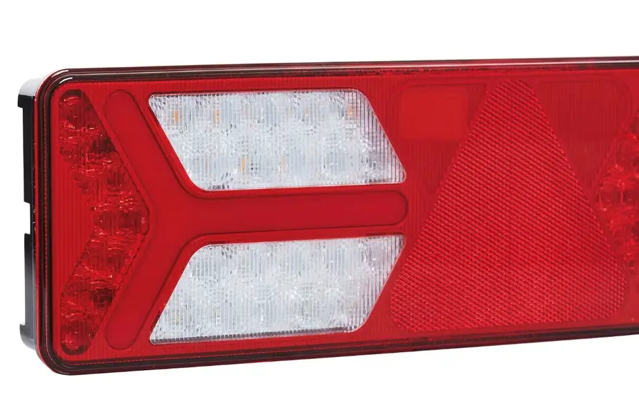 Red polycarbonate tail light lens with clear backup light sections showing textured plastic surface patterns