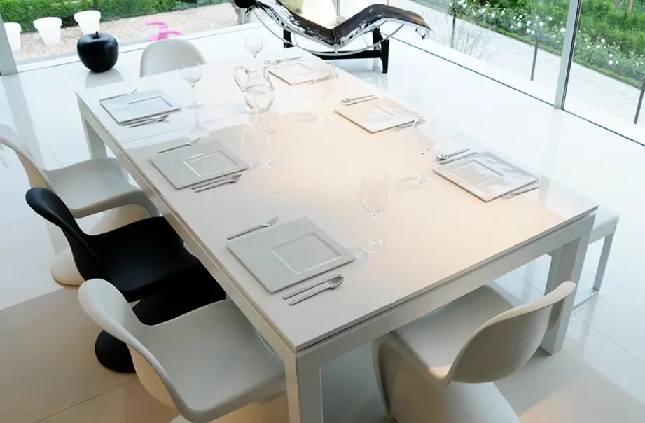 A white outdoor powder-coated table surrounded by a bench and several chairs