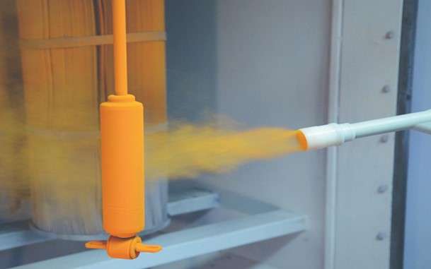 a machinist using a corona spray gun for powder coating to powder-coat a metal component