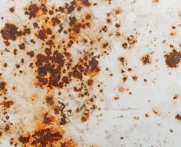 An originally grey metal surface now with numerous spots of brown discoloration