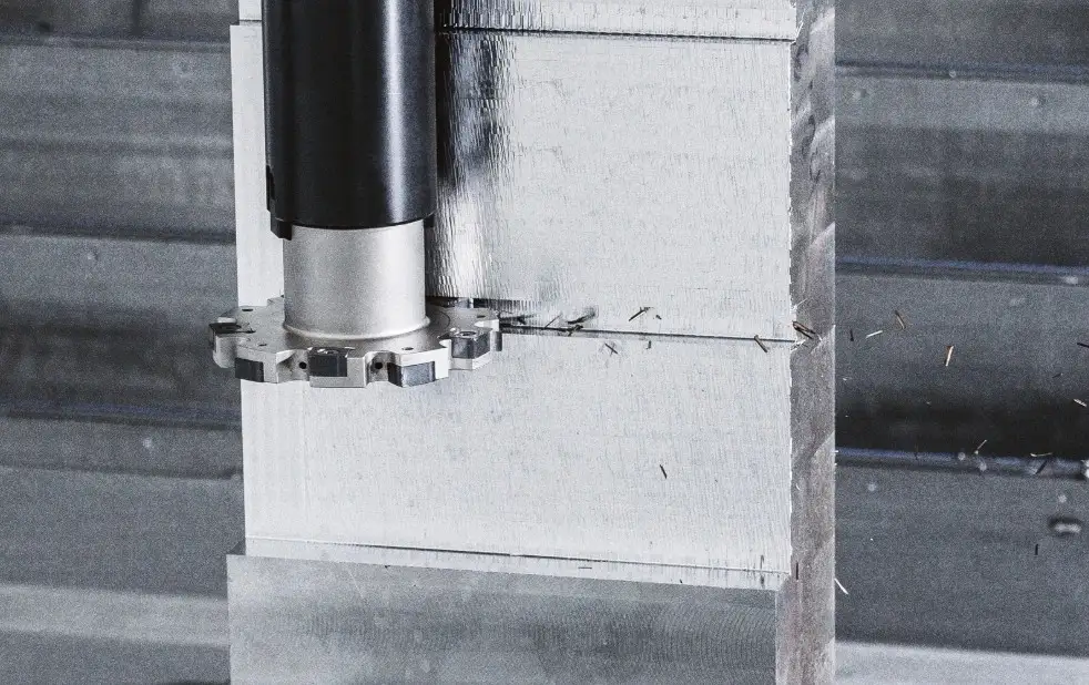 A metal block being side-milled by a fast-rotating tool