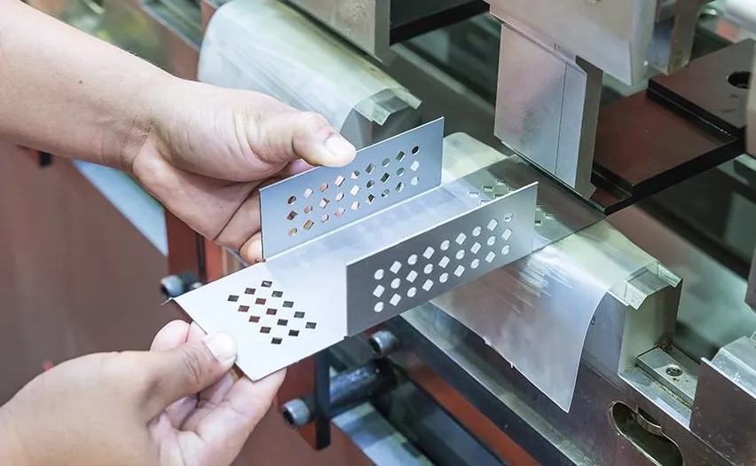 Hands holding a bracket of titanium having diamond-shaped holes in it